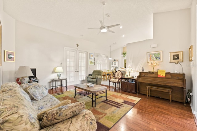 living room featuring hardwood / wood-style floors, lofted ceiling, french doors, ceiling fan, and a textured ceiling