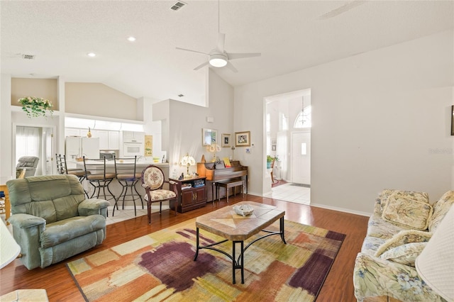 living room with light hardwood / wood-style floors, high vaulted ceiling, and ceiling fan