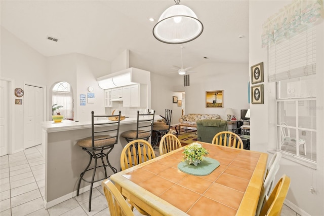 dining space with ceiling fan, lofted ceiling, and light tile patterned flooring