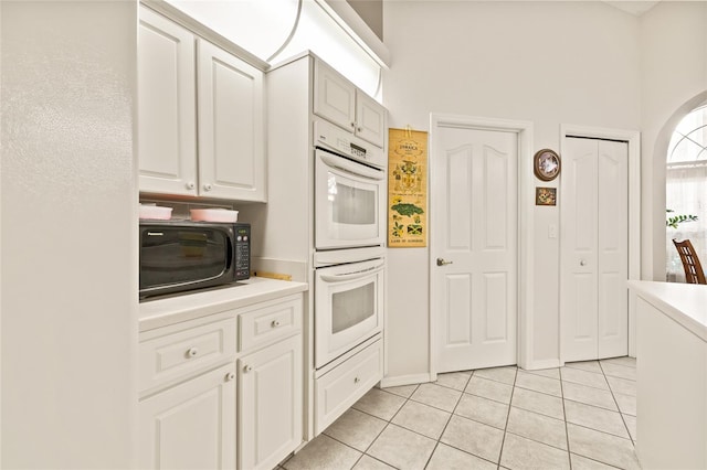 kitchen with light tile patterned floors, white double oven, and white cabinetry