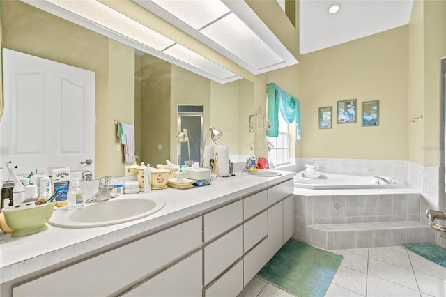 bathroom with tiled tub, tile patterned flooring, and vanity