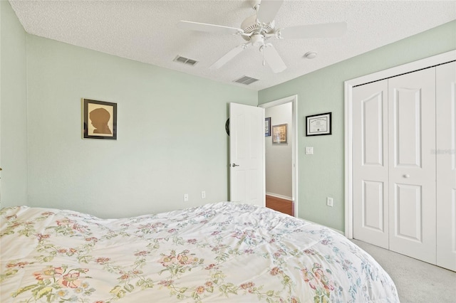 carpeted bedroom with ceiling fan, a textured ceiling, and a closet