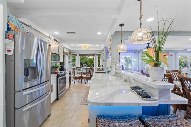 kitchen featuring kitchen peninsula, stainless steel appliances, decorative light fixtures, and plenty of natural light