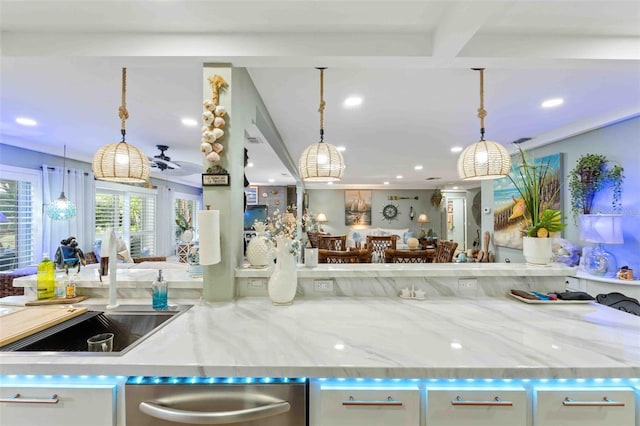 kitchen with stainless steel dishwasher, light stone counters, ceiling fan, and decorative light fixtures