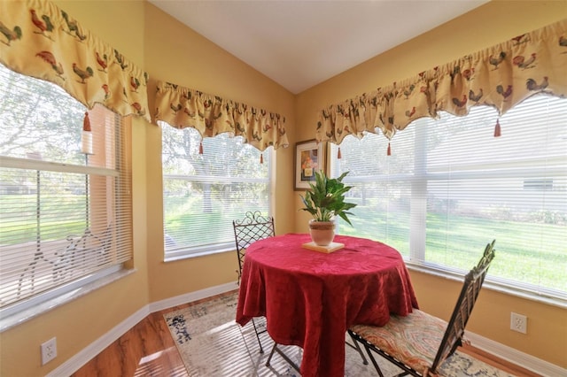 dining space with wood-type flooring and vaulted ceiling