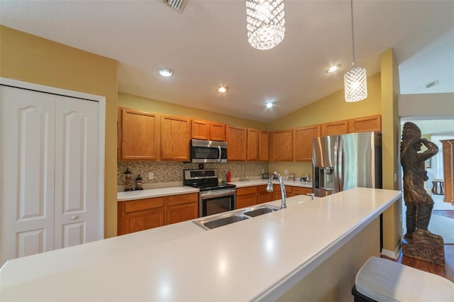 kitchen with a kitchen bar, vaulted ceiling, sink, pendant lighting, and appliances with stainless steel finishes