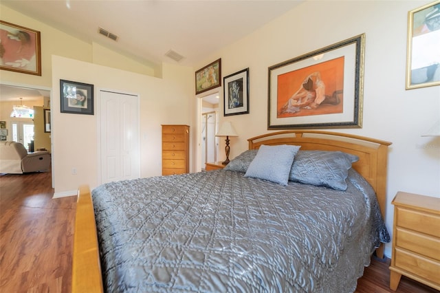 bedroom with a closet, vaulted ceiling, and dark hardwood / wood-style floors