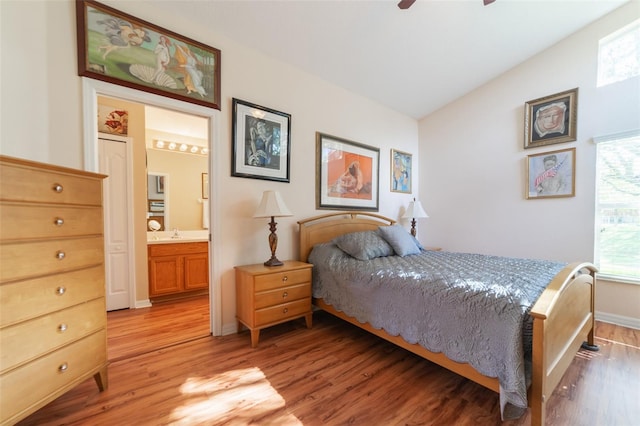 bedroom with light wood-type flooring, sink, vaulted ceiling, ceiling fan, and ensuite bathroom