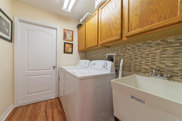 laundry area with cabinets, hardwood / wood-style flooring, sink, and washer and clothes dryer