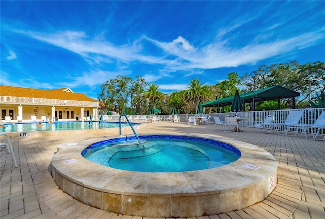 view of swimming pool featuring a hot tub and a patio area