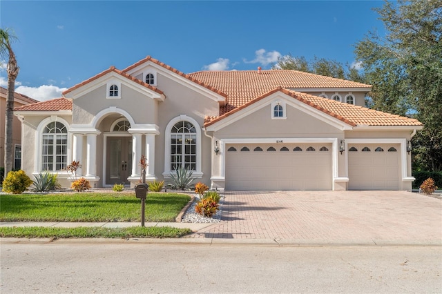 mediterranean / spanish home with a garage and a front lawn