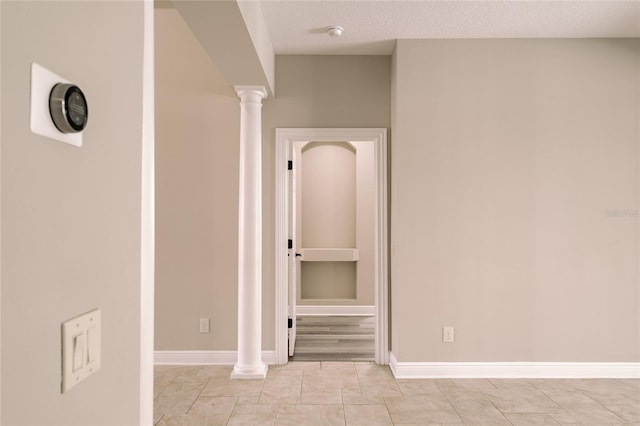 hallway featuring ornate columns and a textured ceiling