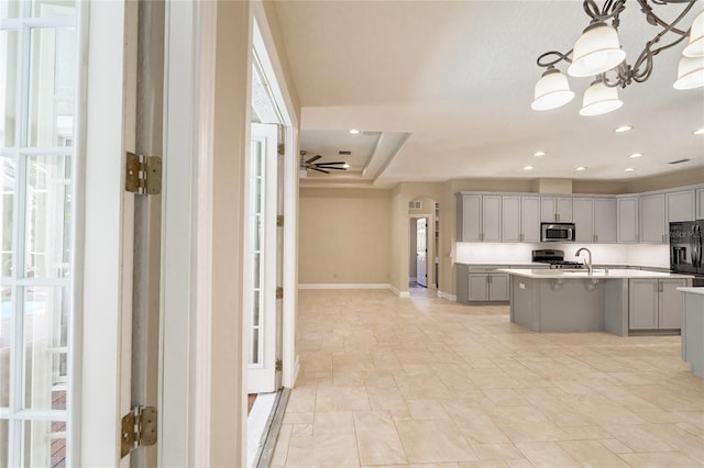 kitchen with gray cabinets, plenty of natural light, a center island with sink, and black fridge with ice dispenser