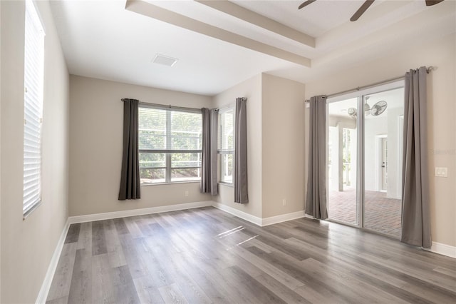 empty room featuring ceiling fan, wood-type flooring, and a raised ceiling