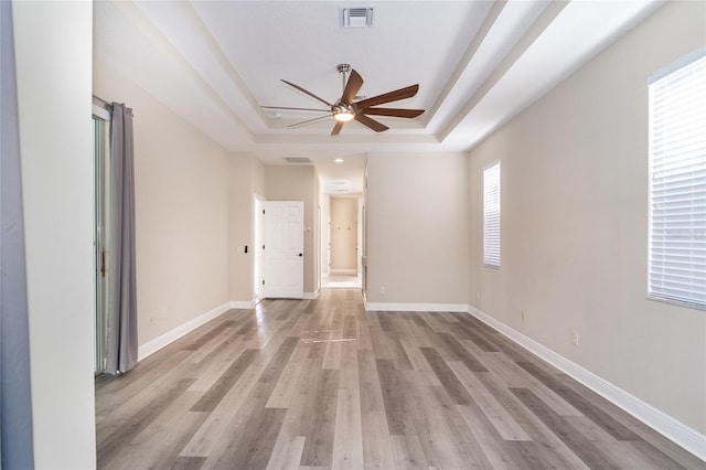 spare room featuring a raised ceiling, ceiling fan, and light hardwood / wood-style floors