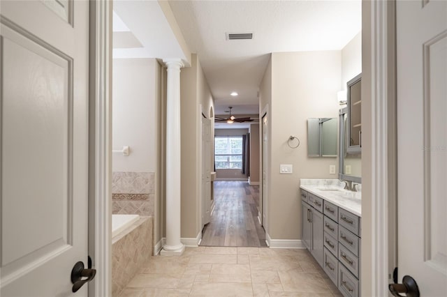 bathroom with ornate columns, vanity, ceiling fan, tiled bath, and tile patterned flooring