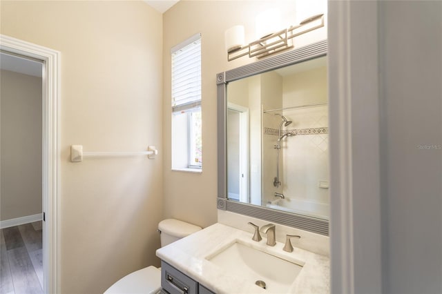 full bathroom featuring tiled shower / bath, wood-type flooring, vanity, and toilet