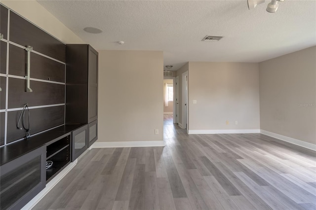 unfurnished living room featuring hardwood / wood-style flooring and a textured ceiling