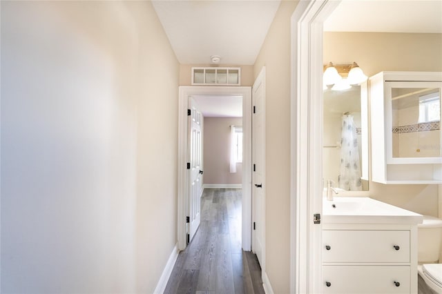 corridor with sink and dark wood-type flooring