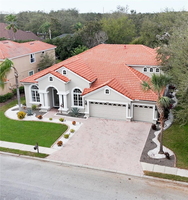 mediterranean / spanish-style home with a garage and a front lawn