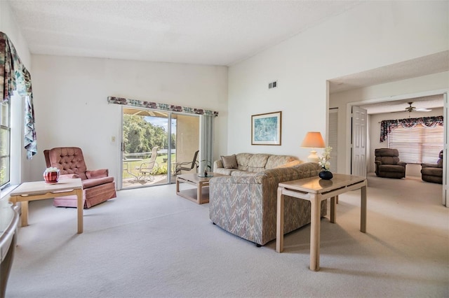 carpeted living room featuring ceiling fan and a textured ceiling