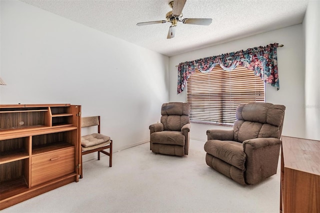 sitting room featuring carpet, a textured ceiling, and ceiling fan