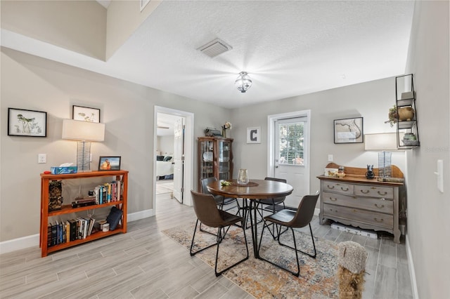 dining space with a textured ceiling and light hardwood / wood-style flooring