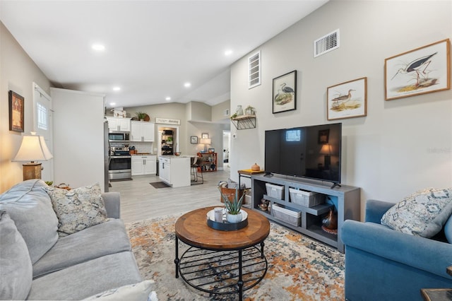 living room featuring light hardwood / wood-style flooring and vaulted ceiling