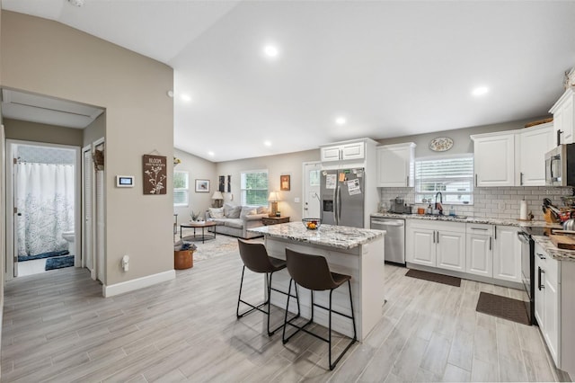 kitchen featuring light hardwood / wood-style flooring, appliances with stainless steel finishes, lofted ceiling, and a center island