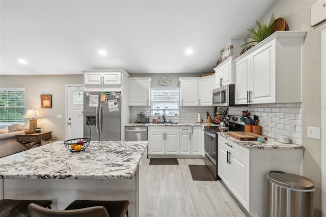 kitchen with white cabinets, stainless steel appliances, sink, and plenty of natural light