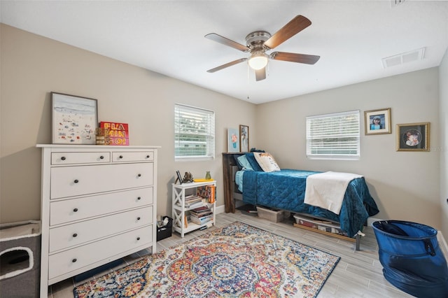 bedroom featuring light hardwood / wood-style floors, multiple windows, and ceiling fan