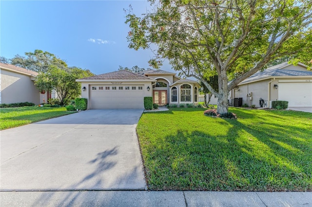 ranch-style home with a garage, cooling unit, and a front lawn