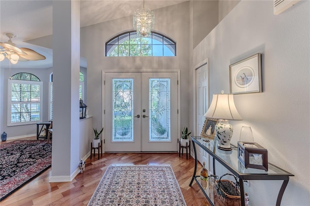 entryway with vaulted ceiling, ceiling fan with notable chandelier, light hardwood / wood-style flooring, and french doors