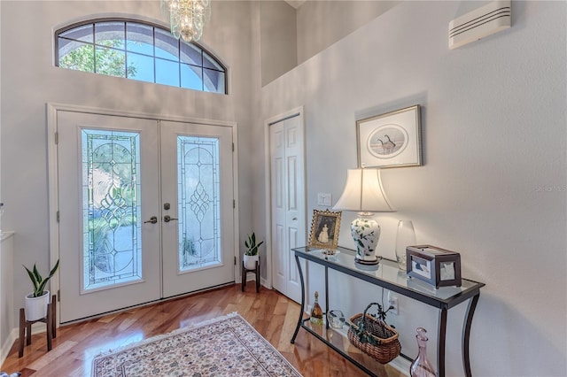 foyer with a high ceiling, french doors, light hardwood / wood-style floors, and plenty of natural light