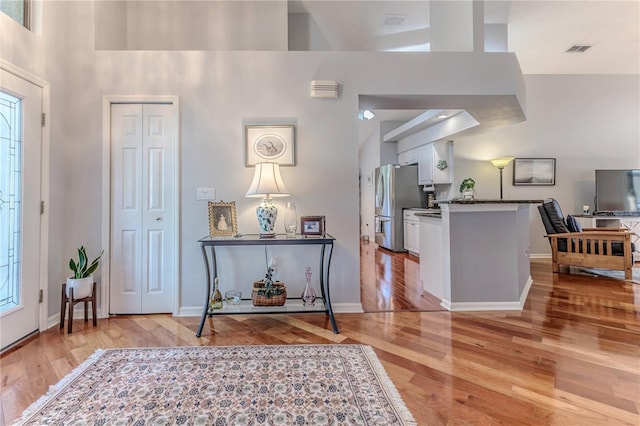 foyer with light wood-type flooring and high vaulted ceiling