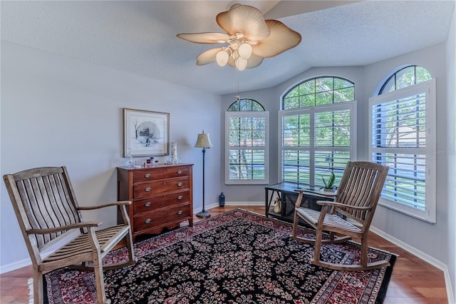 living area featuring ceiling fan, lofted ceiling, hardwood / wood-style floors, and a healthy amount of sunlight