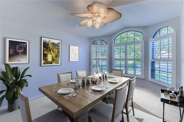 carpeted dining space featuring a textured ceiling, lofted ceiling, and ceiling fan