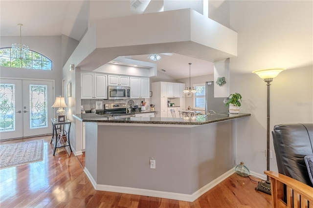 kitchen with white cabinets, kitchen peninsula, decorative light fixtures, and stainless steel appliances