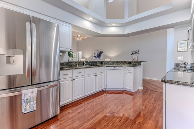 kitchen featuring white cabinets, kitchen peninsula, appliances with stainless steel finishes, and wood-type flooring