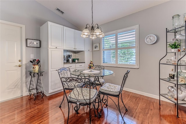 dining area featuring hardwood / wood-style floors, lofted ceiling, and a notable chandelier