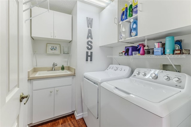 laundry room featuring dark hardwood / wood-style flooring, cabinets, a textured ceiling, sink, and washing machine and clothes dryer