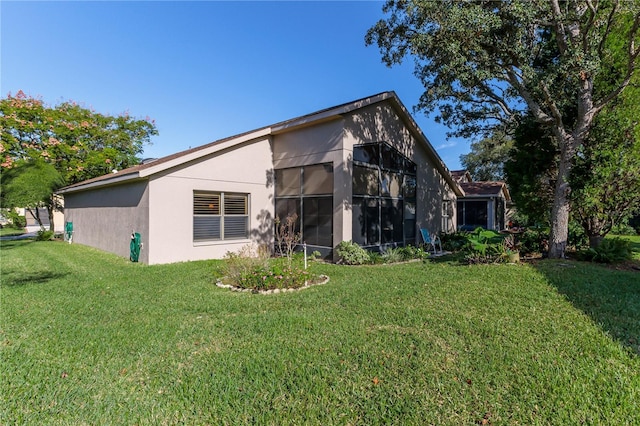 back of property with a sunroom and a lawn