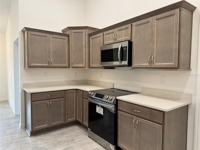 kitchen featuring range with electric stovetop, light stone countertops, and dark brown cabinets