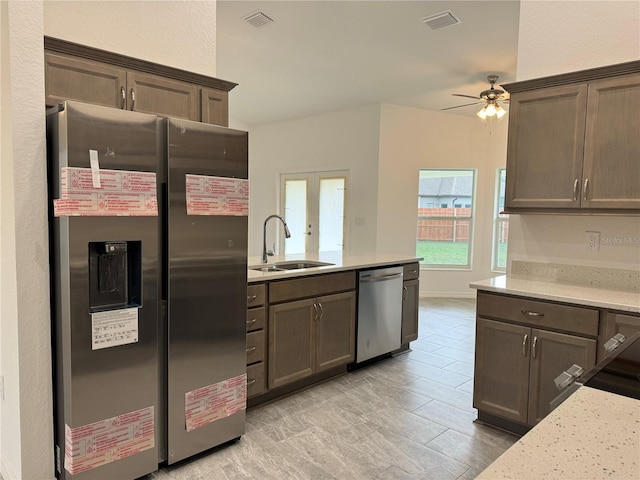 kitchen with light stone countertops, ceiling fan, sink, stainless steel appliances, and french doors