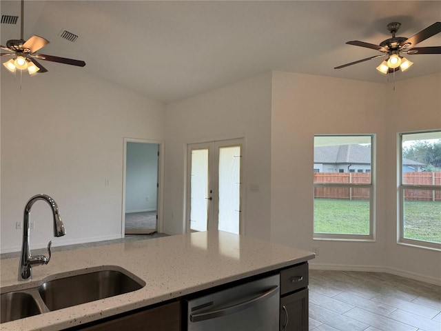 kitchen featuring light stone countertops, stainless steel dishwasher, ceiling fan, sink, and light hardwood / wood-style flooring