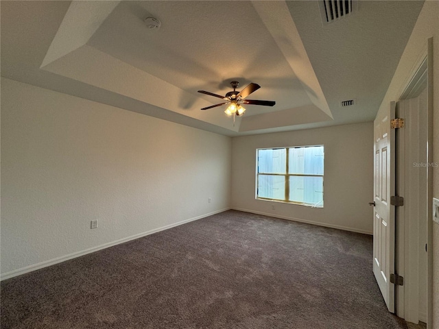 carpeted empty room with ceiling fan, a textured ceiling, and a tray ceiling