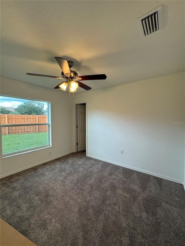 unfurnished room featuring dark colored carpet, a textured ceiling, and ceiling fan