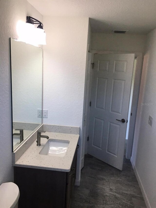 bathroom featuring vanity, toilet, and a textured ceiling