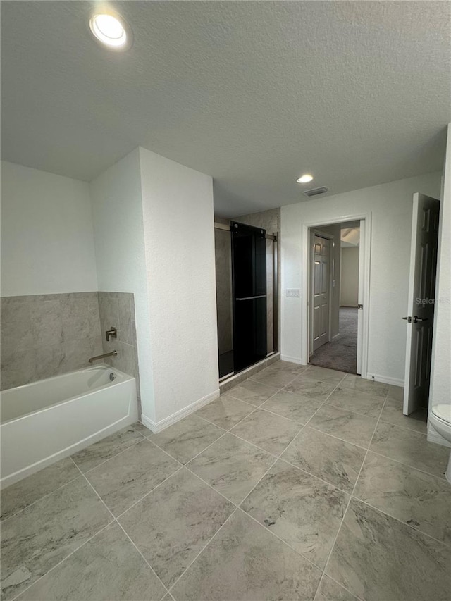 bathroom featuring tile patterned flooring, a textured ceiling, toilet, and a tub