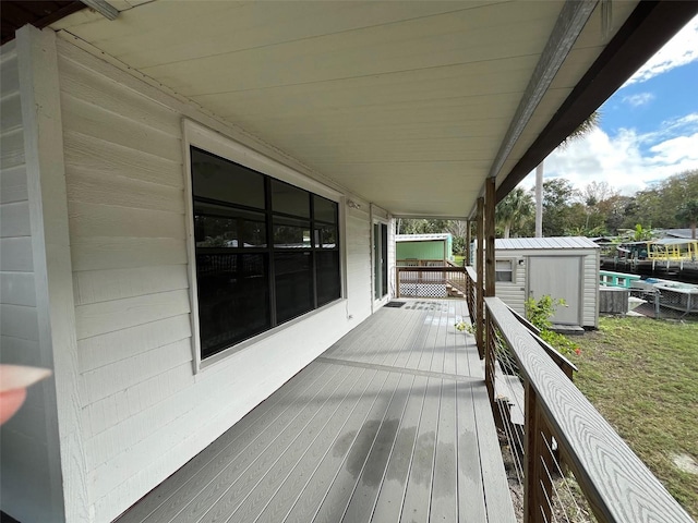 wooden terrace with a storage unit, an outbuilding, and a yard
